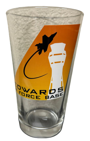 A beer glass with a logo that includes an illustration of a jet and a control tower, and the text 'EDWARDS FORCE BASE'.